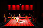 Darsteller*innen sthen auf einem rot erleuchteten Bühnenboden