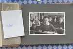 Auf dem Bild sieht man ein Fotoalbum, welches aufgeklappt ein schwarz-weiß Foto eines Jungen zeigt, der mit anderen Jungs in einem Klassenzimmer sitzt. Neben dem Foto sieht man einen Zettel mit dem Namen "Herbert" drauf.