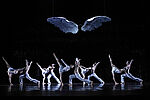 Ein Ballettensemble tanzt unter einem großen Flügelpaar, das von der Decke hängt