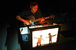 Lasse Wagner mit Gitarre hinter einem kleinen Schattentheater