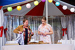 Zacharias Preen als Lionel und Isabel Baumert als Celia stehen in einem Partyzelt und blicken auf ein Brot.