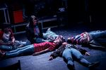Eine Gruppe von Jugendlichen liegt sternförmig verteilt auf dem Boden, während zwei weitere neben ihnen sitzen.