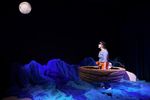 Eine Schauspielerin in einem kleinen Boot schaut zum hellen Mond