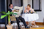 Zacharias Preen als Toby und Isabel Baumert als Celia sitzen am Frühstückstisch, er liest Zeitung.