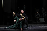Andeka Gorrotxategi  als ohnmächtiger Otello wird von Dario Solari als Jago wie ein Beutetier präsentiert. Herren des Opernchores sehen aus der Ferne zu.