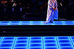 Eine Frau steht auf einem blau beleuchteten Bühnenboden