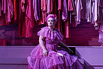 Eine Frau sitzt in einem pink-gerüschten Kleid vor einem Kleiderschrank