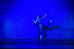 Eine Tänzerin lehnt sich an einer blauen Wand an.