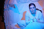 Patricia Windhab als Gregor Samsa in einem weißen Kokon sitzend