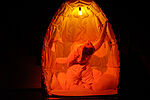 Patricia Windhab als Gregor Samsa in einem Kokon, der orange ausgeleuchtet wird
