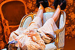 Eine Frau liegt in Hausschuhen auf einer Chaiselongue mit hochgelegten Beinen