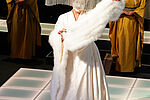 Eine Frau trägt ein weißes Kostüm mit Pelz und träft einen großen Hut, darunter ist sie japanisch geschminkt