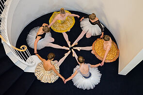 Junge Ballerinas sitzen im Kreis auf dem Boden