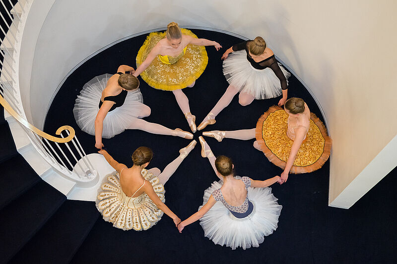 Junge Ballerinas sitzen im Kreis auf dem Boden