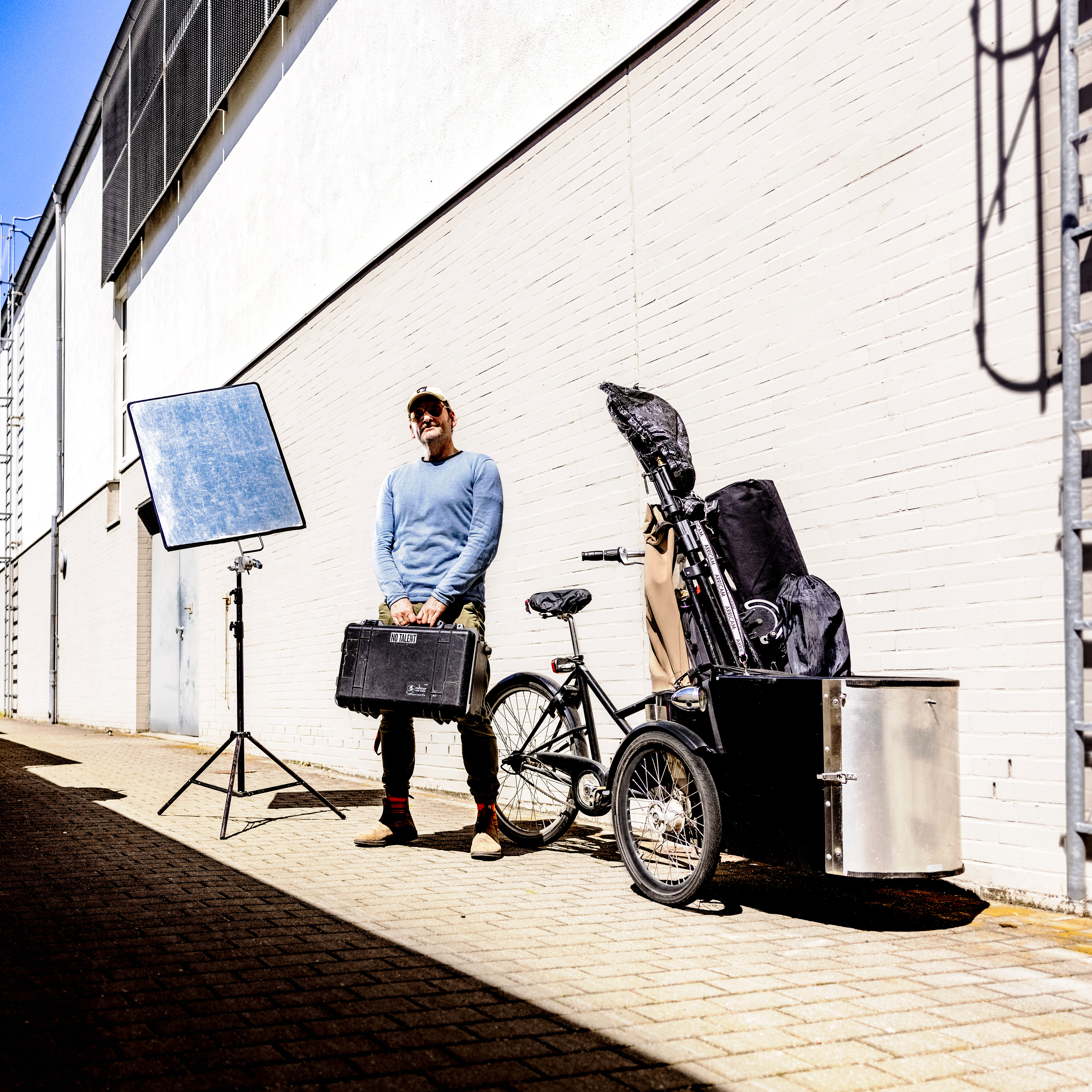 Ein Mann steht mit Fotoequipment vor einem Lastenfahrrad