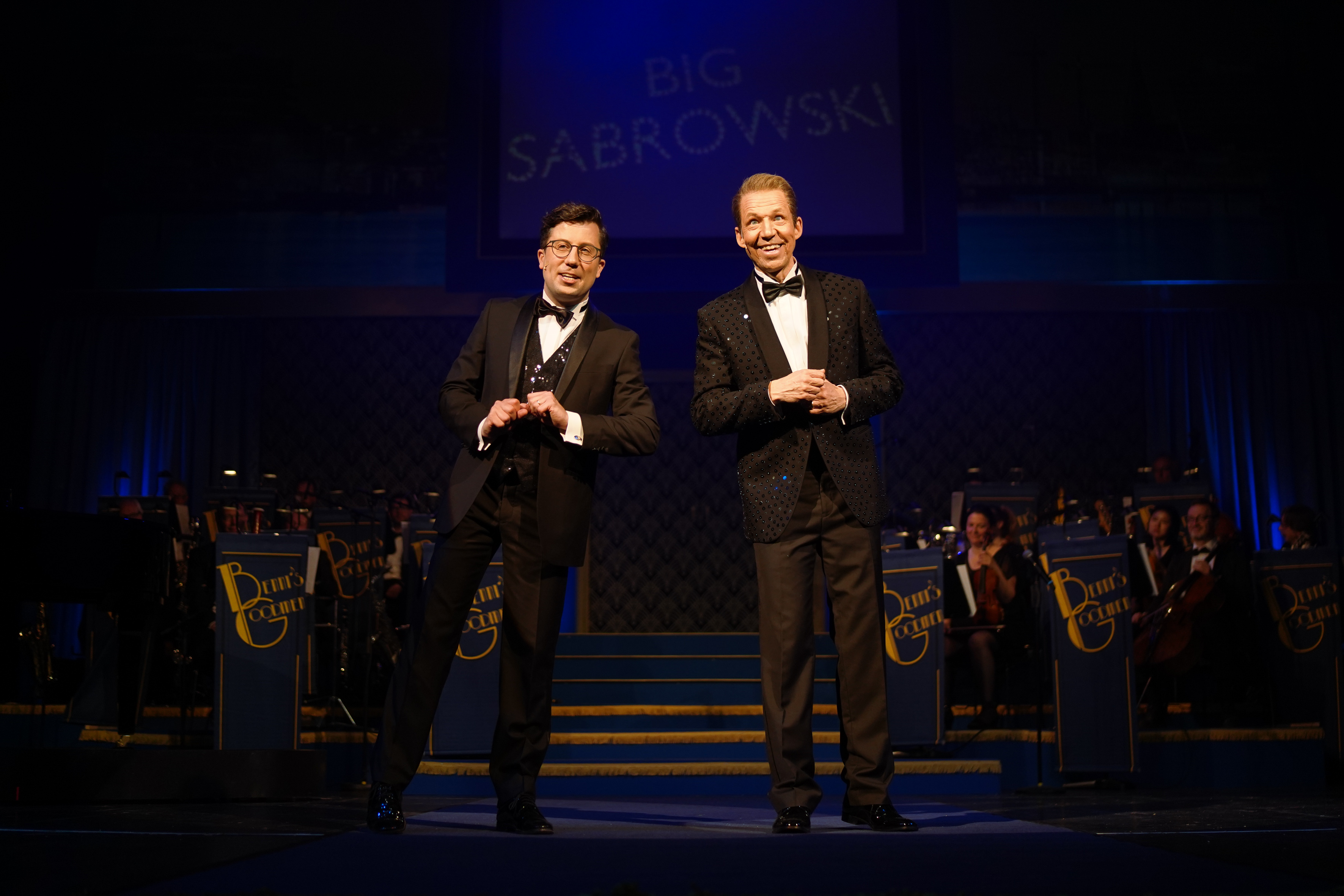 Zwei Männer stehen in Anzügen auf einer Bühne